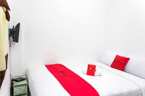 加拉旺RedDoorz @ Galuh Mas的客房内的白色床和红色枕头