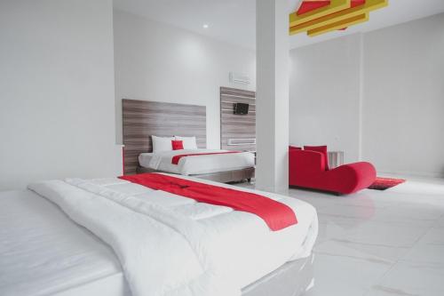 沃诺索博RedDoorz Syariah @ Jalan Dieng的白色卧室配有两张床和红色椅子