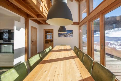 皮伊圣万桑Maison Puy Saint Vincent的一间带长桌和绿色椅子的用餐室