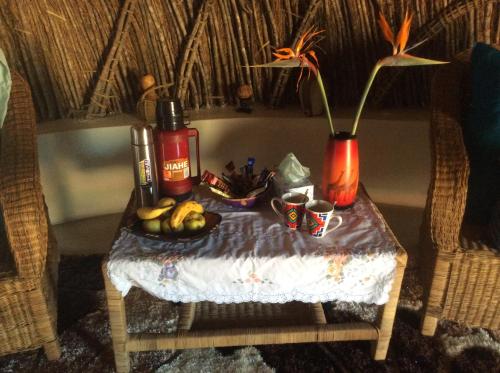 UsutuSwazi Dreams. (Nqabaneni Eco-Volunteering.)的一张桌子,上面有花瓶和一碗水果