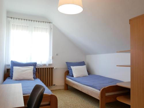 TerényHerőke Vendégház的客房设有两张床、一张桌子和一扇窗户。