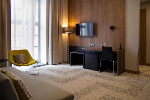 格但斯克IBB Hotel Gdańsk的酒店的客房,配有书桌和墙上的电视