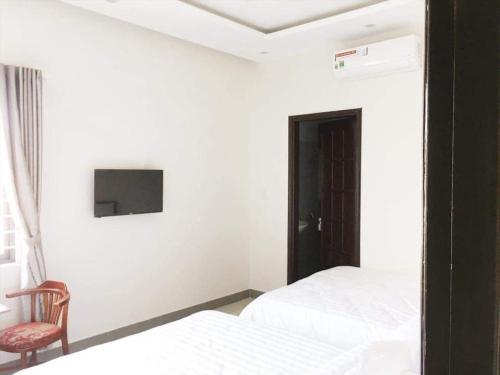 岘港Motel Thanh Long的一间卧室设有两张床,墙上配有电视。