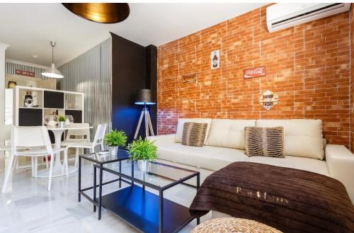 赫雷斯-德拉弗龙特拉Apartamento semi-industrial palacio Castilla的客厅配有白色沙发和砖墙