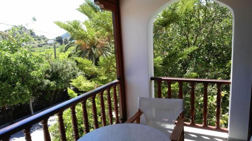 托隆Villa Christina的阳台配有桌子和树木繁茂的窗户。