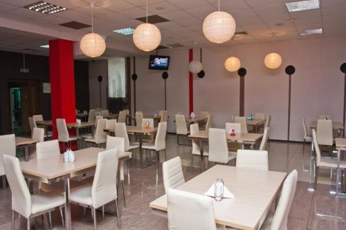 赤塔大城市酒店的用餐室配有桌子和白色的椅子及灯
