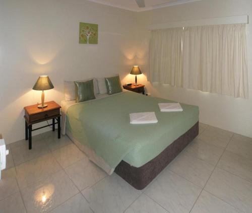 凯恩斯特拉韦德麦克劳德假日公寓的一间卧室配有一张绿色大床和两盏灯。