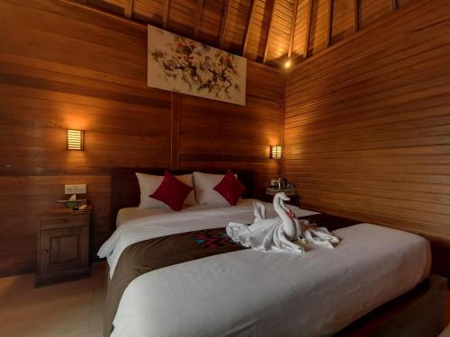 珀尼达岛Kamasan Cottage的一间卧室配有一张带两个天鹅的床