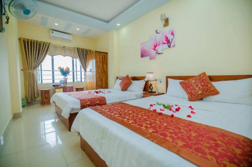 吉婆岛Cat Ba Bay Vision Hotel的酒店客房,配有两张带鲜花的床