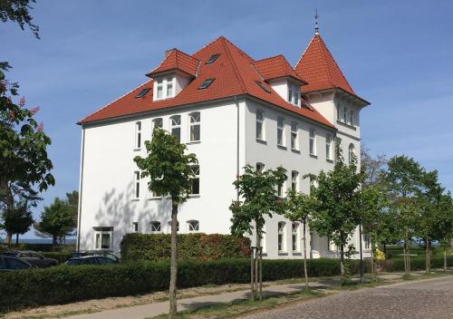 宾茨Hotel Pension Haus Colmsee的一座白色的大建筑,有红色的屋顶