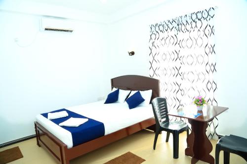 亭可马里Blue Diamond Resort的卧室配有1张床、1张桌子和1把椅子