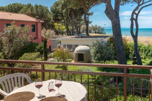 阿尔比尼娅Camping Village Bocche D'Albegna的俯瞰大海的阳台的桌子和酒杯