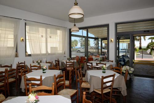 瓦拉泽Hotel Ristorante Milton的餐厅设有白色的桌椅和窗户。