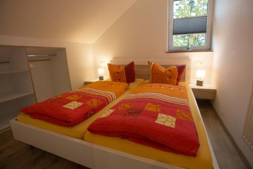 洛默Fewo Ben的一间卧室配有两张带橙色和红色毯子的床