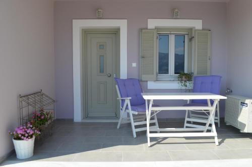 阿索斯浪漫曲一室公寓酒店的庭院配有紫色椅子和白色桌子