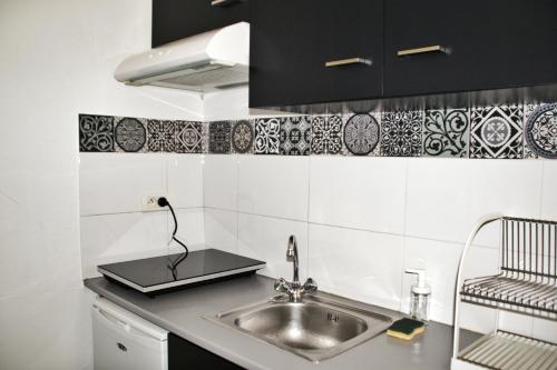 蒙彼利埃La Fontaine - Studio Ecusson的厨房设有水槽和黑白瓷砖