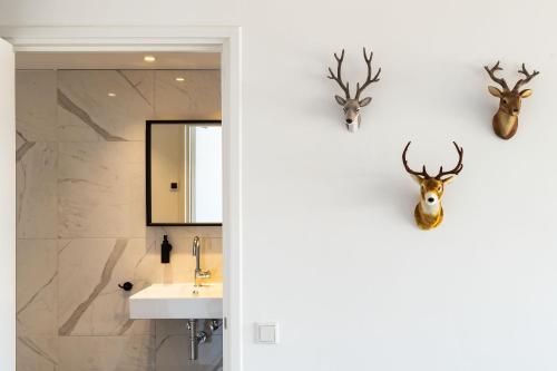 赞德沃特Paulus Loot Zandvoort的墙上设有带水槽和鹿头的浴室