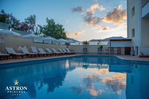 卡尔帕索斯天文公主酒店的一个带椅子的游泳池,日落