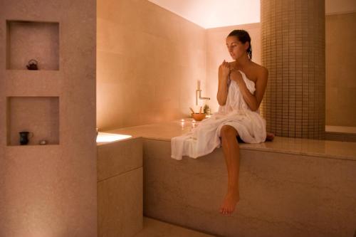 圣吉米纳诺Villasanpaolo Resort & Spa的坐在浴缸上身穿白色衣服的女人