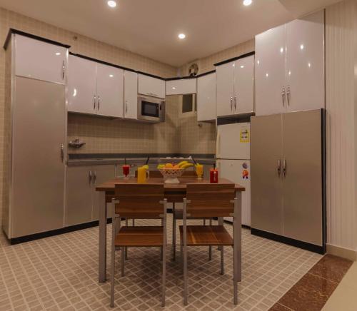 塔伊夫Nukhbat Al Makan Apartment Hotel的厨房配有白色橱柜和桌椅