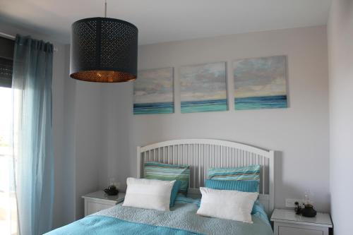 多列毛利诺斯Suite Home Los Alamos sol, playa y golf , parking&Wifi的一间卧室配有一张带蓝色和白色枕头的床