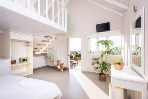 玛利亚诺托斯高地套房公寓式酒店的一间白色的卧室,配有床和楼梯