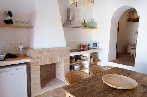 莫托拉Casas de Mértola 33的厨房设有砖砌壁炉和木桌。