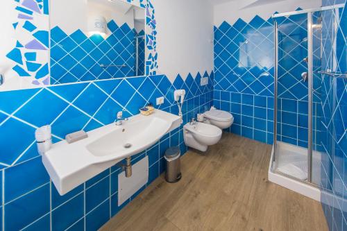 奥尔比亚奥尔比亚城市酒店 的蓝色瓷砖浴室设有水槽和卫生间