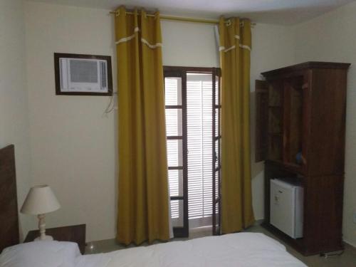 米格尔-佩雷拉Hotel Guararapes的一间卧室配有床、黄色窗帘和窗户