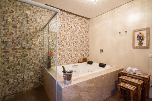 坎波斯杜若尔当Pousada Cantinho da Serra的带浴缸和玻璃淋浴间的浴室。