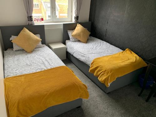 伦敦London budget Maisonette的卧室内的两张床,配有黄色毯子和枕头
