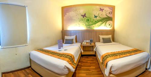坤甸坤甸特蓝瑟雷酒店的墙上画画的房间里设有两张床