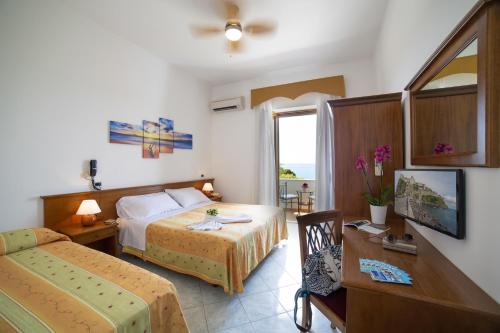 伊斯基亚拉曼多拉酒店的酒店客房设有两张床、一张桌子和一张书桌。