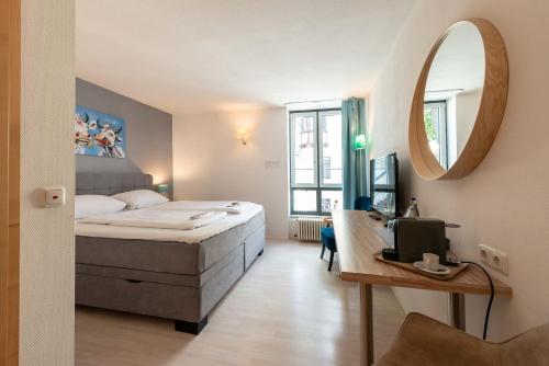班贝格艾姆道姆酒店的一间卧室配有一张床、一张书桌和一面镜子