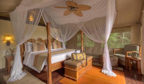 Sekenani萨罗瓦玛拉野生宿营地的一间卧室配有一张天蓬床和吊扇