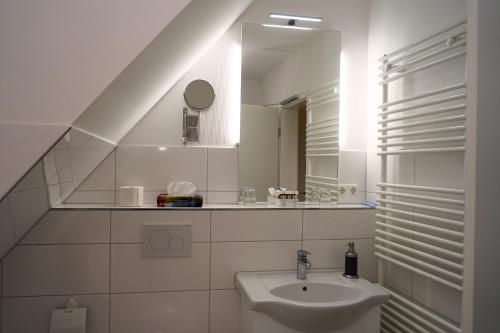 NiesgrauOstseehotel Hunhoi的白色的浴室设有水槽和镜子