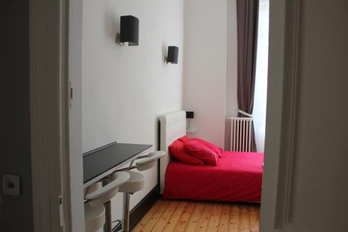 里尔Les Cariatides的一间卧室配有红色的床和一台平面电视