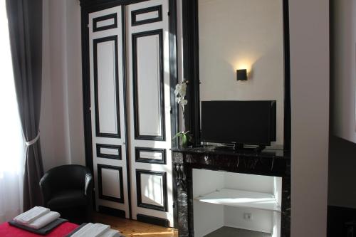 里尔Les Cariatides的一间设有一扇门的房间,配有电视和镜子