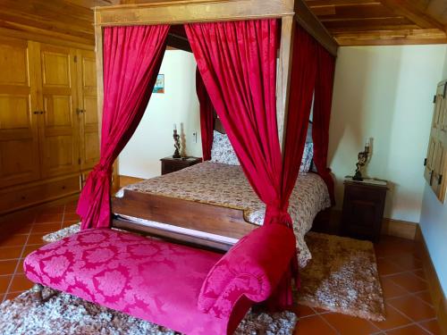 维埃拉·多米尼奥佩尼拉乡村民宿的一间卧室配有一张带红色窗帘的天蓬床
