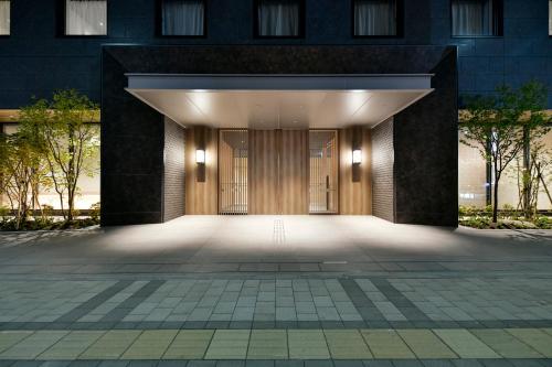 札幌Vessel Hotel Campana Susukino的一座带大木门的建筑的入口