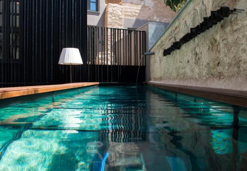 瓦伦西亚卡罗酒店的一座带灯的游泳池,位于一座建筑旁边