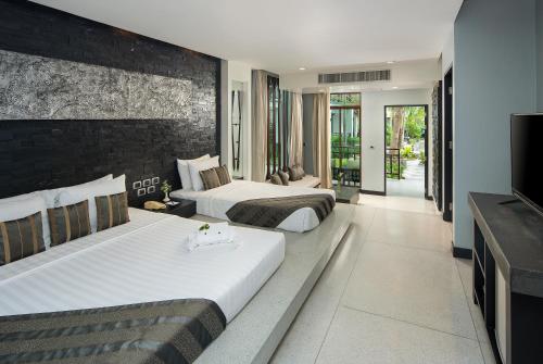 北芭堤雅The Zign Hotel Premium Villa的配有电视的酒店客房内的两张床