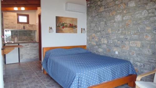 吉奥塔略Paraktio Beach Apartments的一间卧室设有蓝色的床和石墙
