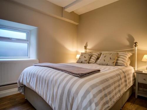 伯福德Mill Race的一间卧室配有带条纹棉被的床和窗户