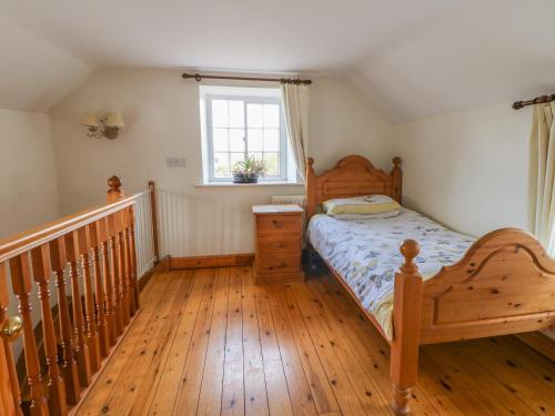 根斯堡Forge Cottage的一间卧室配有一张床,铺有木地板