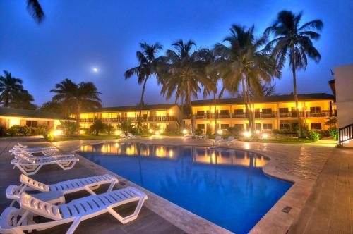 Sere Kunda NDingSunset Beach Hotel的一个带椅子和棕榈树的游泳池的度假酒店
