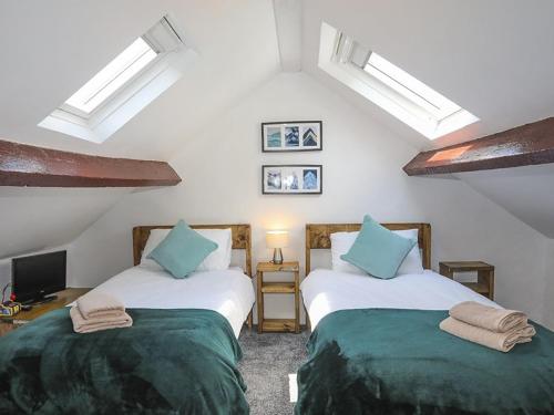 NantlleTan Meredydd的配有白色墙壁和蓝色枕头的客房内的两张床