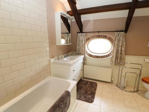 卡林顿The Groom's House的带浴缸、水槽和窗户的浴室