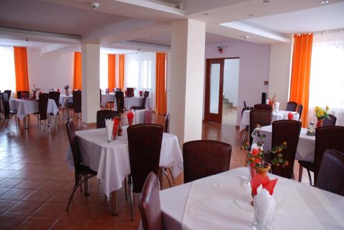 彼得罗沙尼Pensiunea Bujor de Munte的用餐室配有白色的桌椅和橙色窗帘