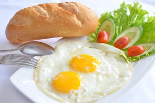 峰牙Phong Nha Orient Hotel的鸡蛋和面包蔬菜的白盘